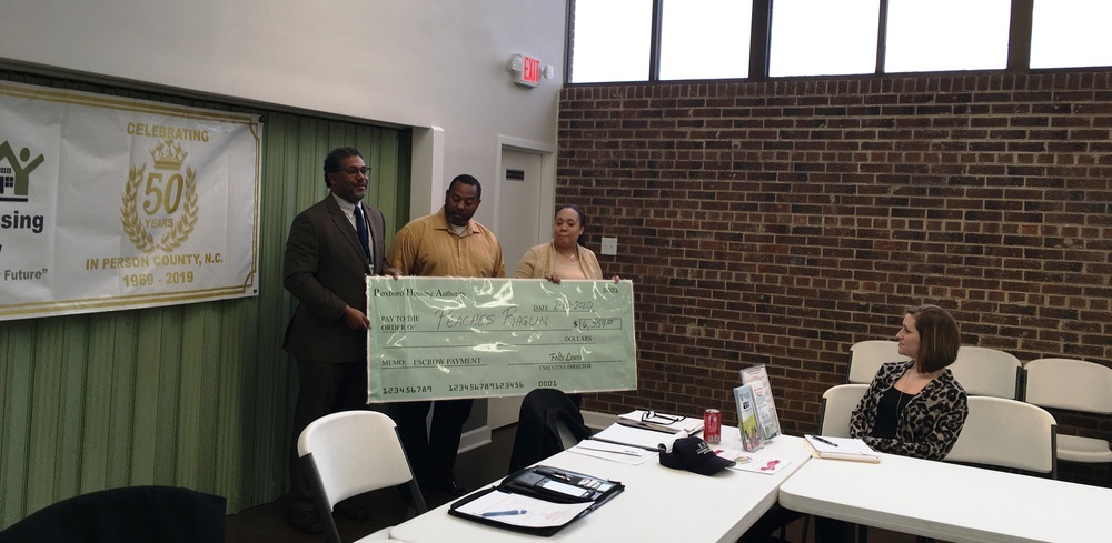 Three people holding a large check.