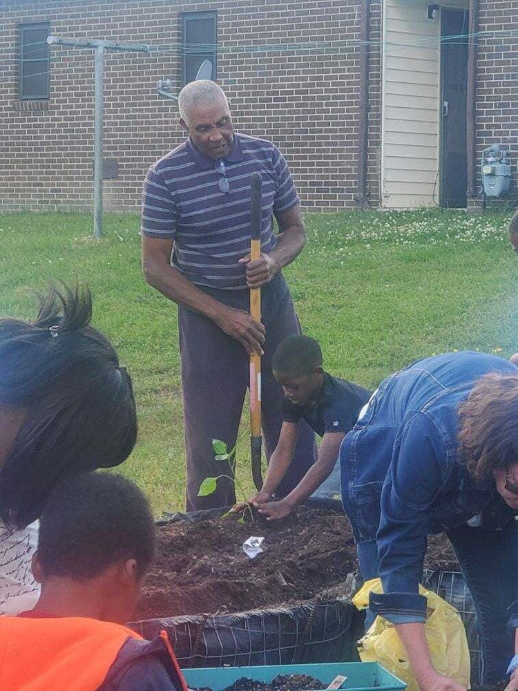 Obie with youth planting tomatoe plant at CJH Garden.
